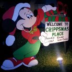 Micky Mouse holding sign "Welcome to Crippsmas Place"